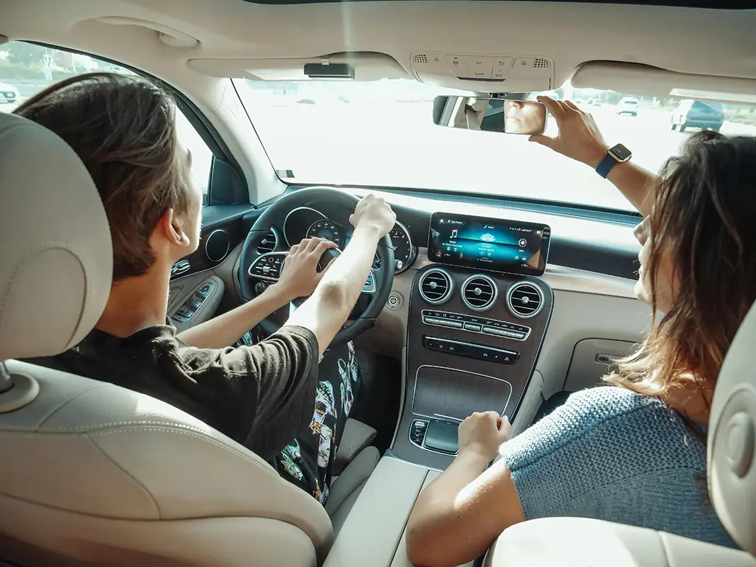 couple in a car on a road trip adjusting the rear view mirror