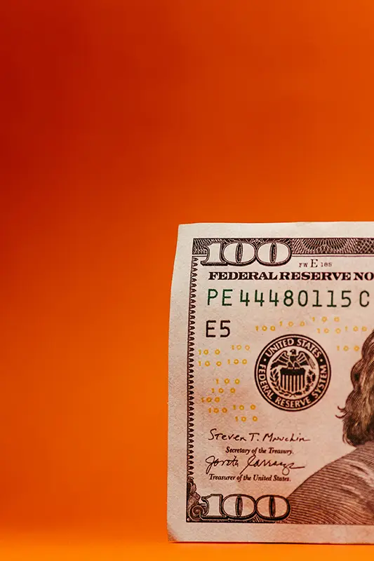 close up of a $100 bill on an orange background