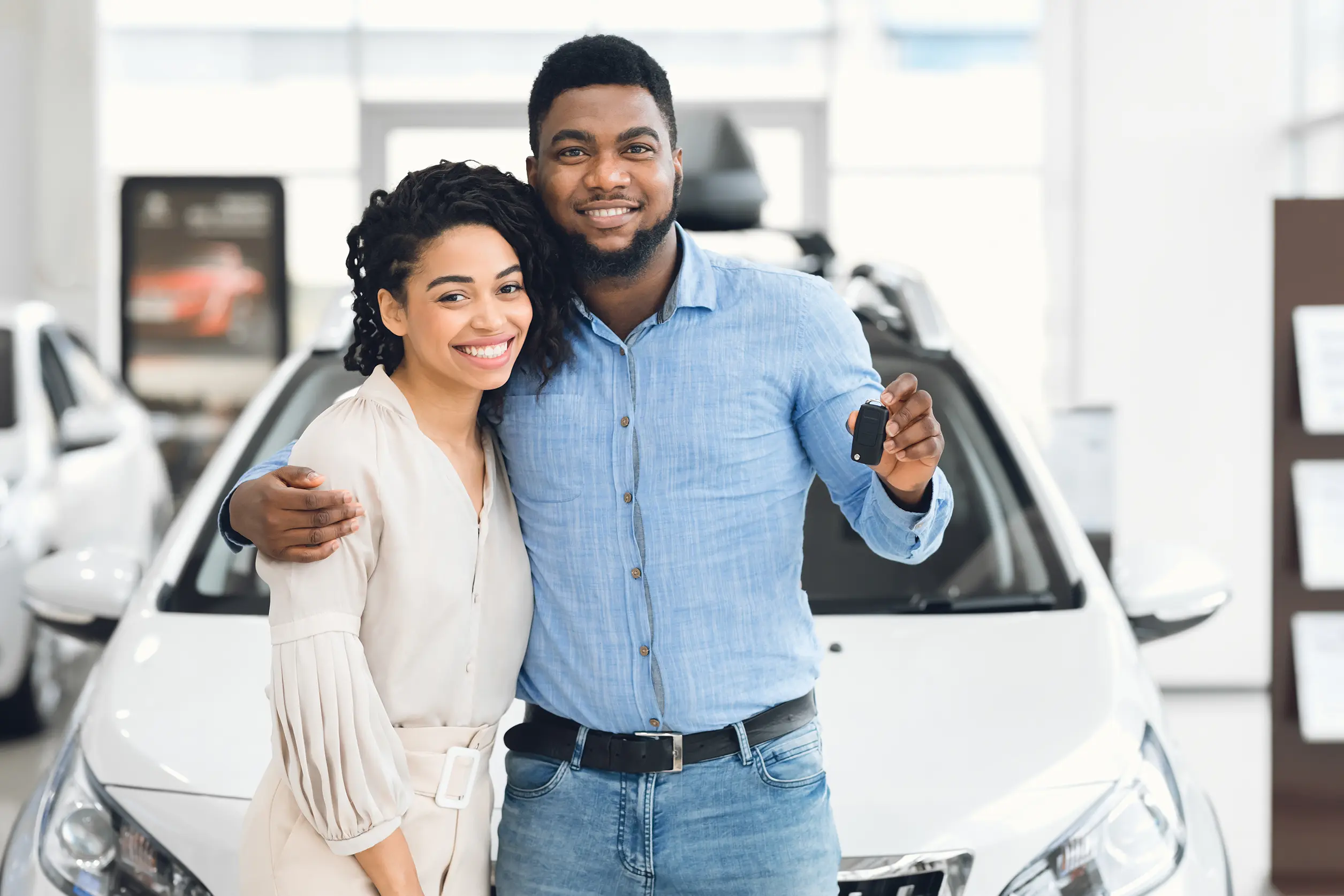 couple standing in front of the car they just purchased