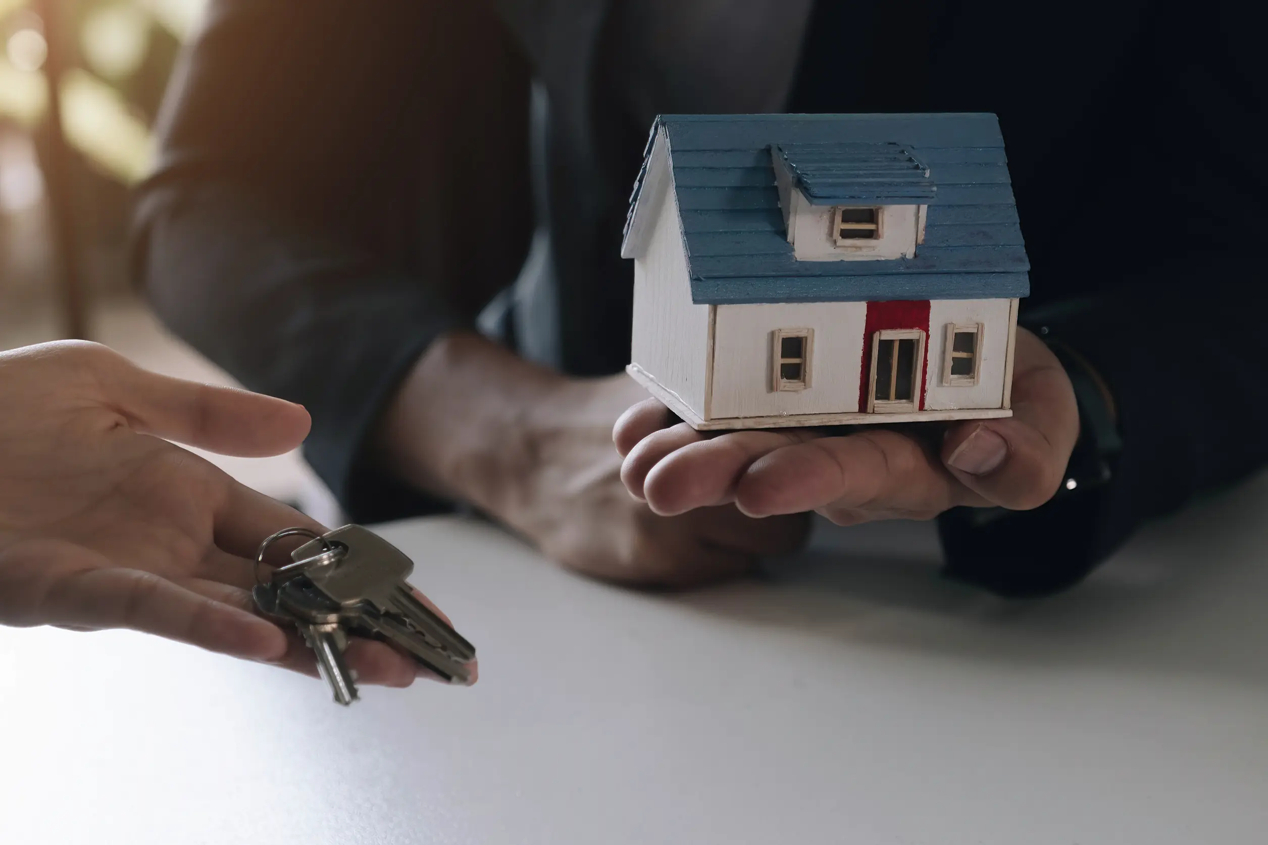 lender holding a tiny house and offering keys